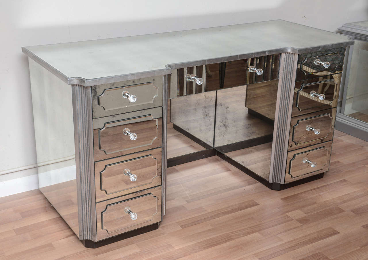 A nine-drawer mirrored dressing table silver gild with distressed mirror. All drawers are lined with new papers with crystal nabs. Black support base. Would also make a lovely console table, desk, dry bar or cabinet!