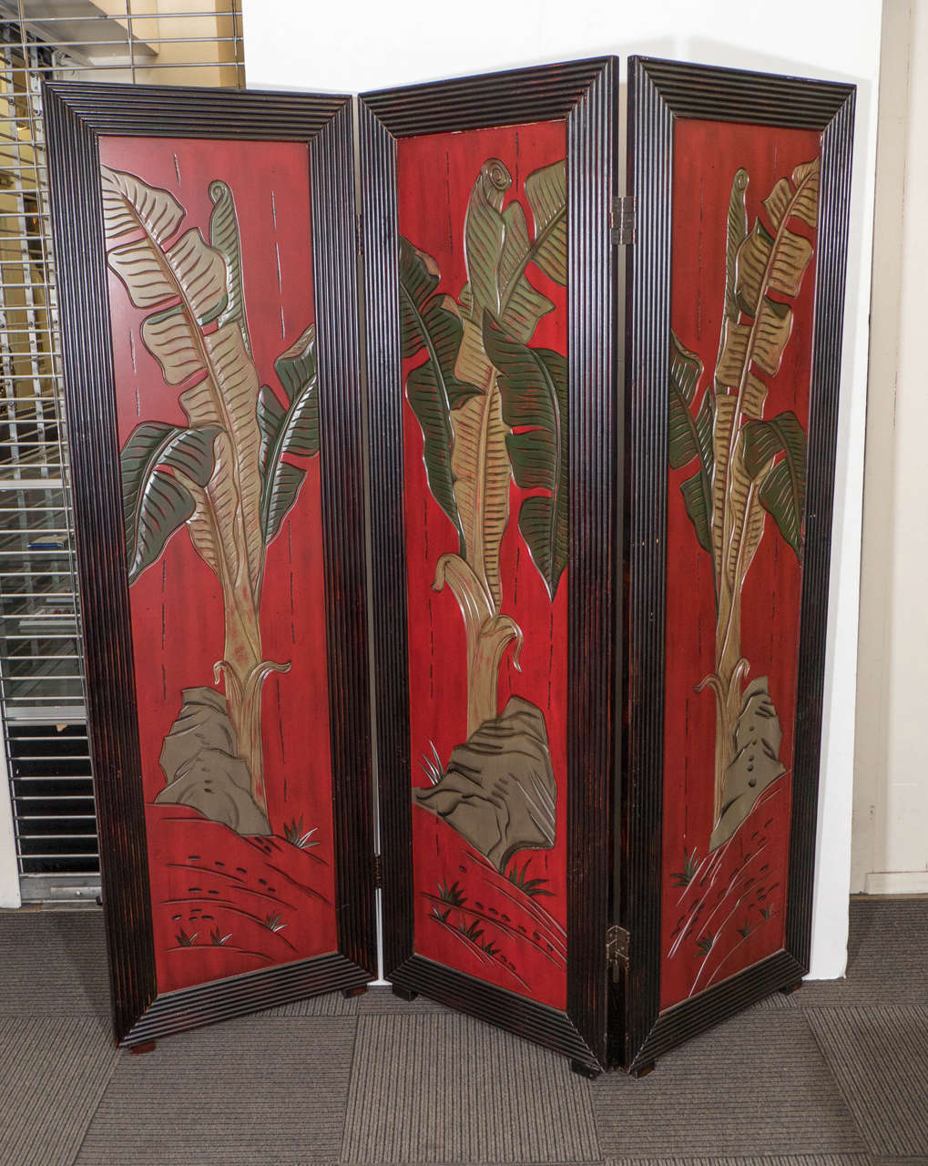 A 20th century Asian three-panel screen or room divider in red with palm leaf decoration. Good vintage condition with age appropriate wear.