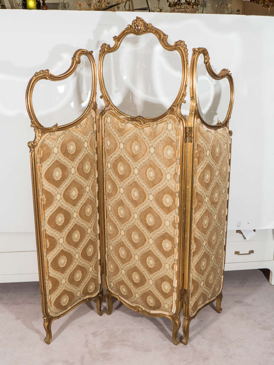 A French gilt wood three-panel screen with beveled glass in framed top, circa 1920s. Upholstered with a beautiful Velvet Elaborate Fabric.Good vintage condition with age appropriate wear.  

Measurements:
Middle panel: 64