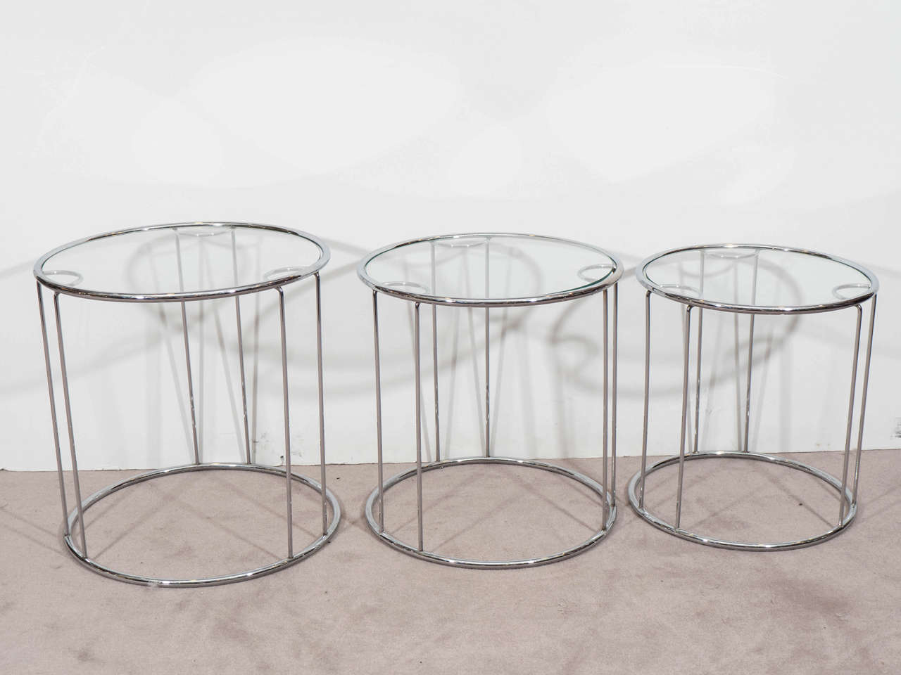 A vintage set of three, cylindrical nesting tables, with chrome and glass tops, designed by Milo Baughman, circa 1960s. Good vintage condition, with age appropriate wear.
