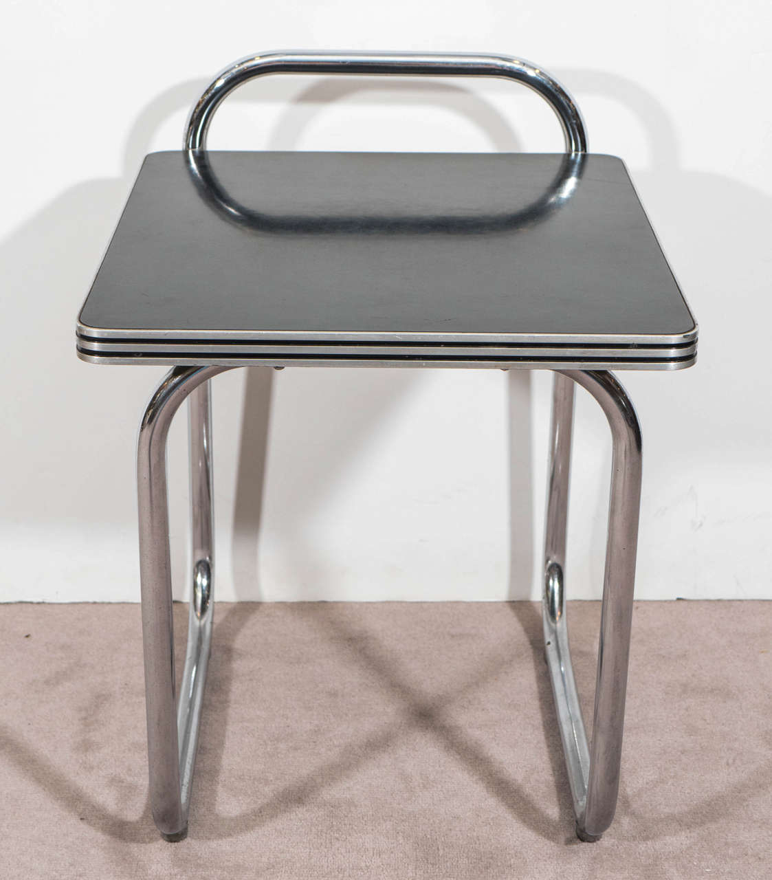 A pair of black laminated end or side tables, on tubular chrome legs, in the style of Bauhaus Era designer Marcel Breuer, produced circa 1930s. Good vintage condition with some age appropriate wear.