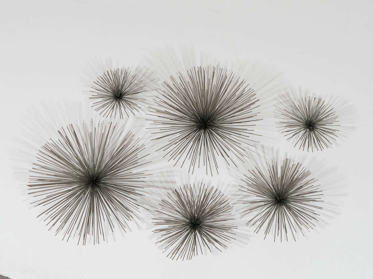 A set of six chrome modernistic spike clusters or pom poms in various sizes, which form a wall sculpture by Curtis Jeré. 

Dimensions: Large 6