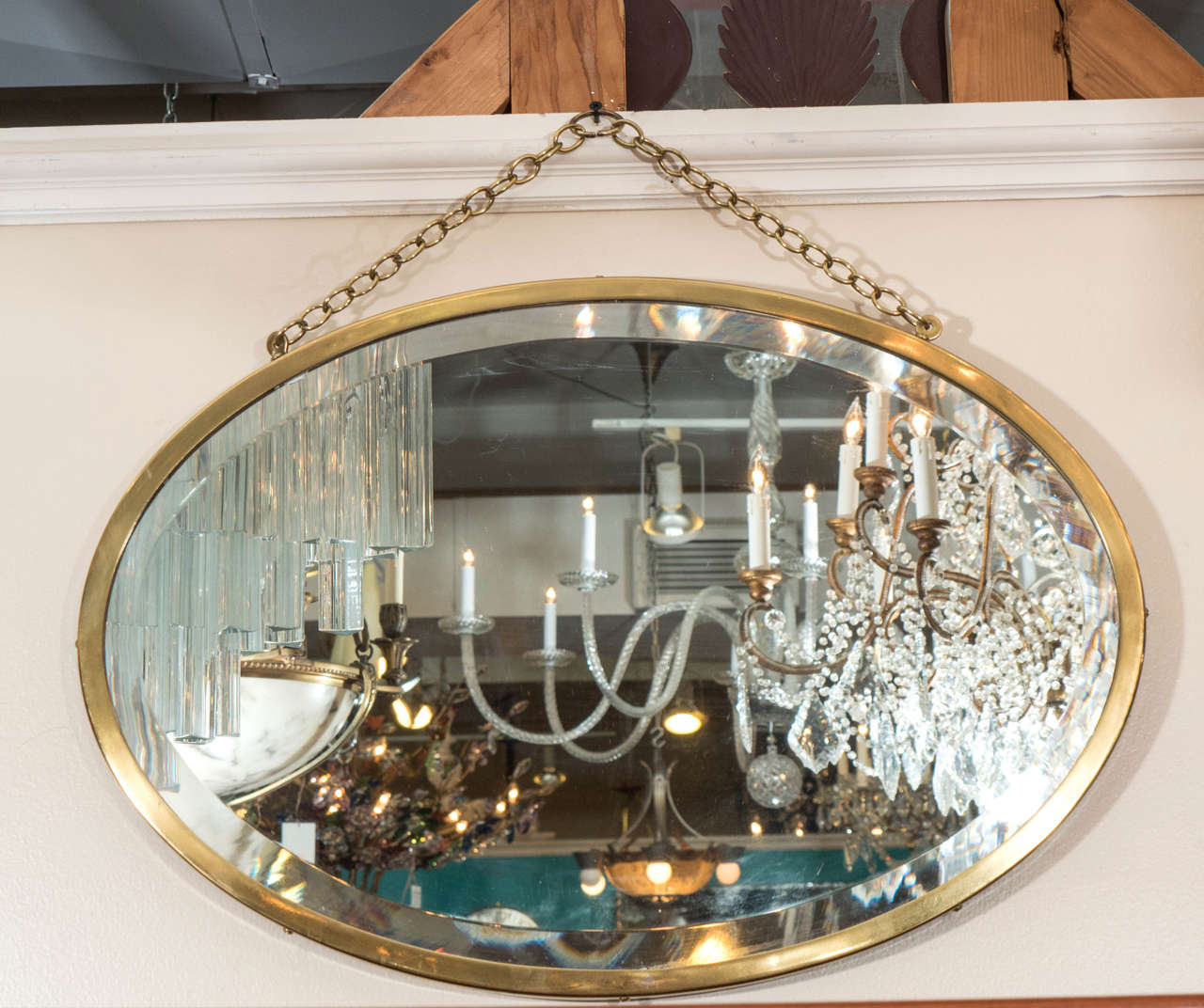 A vintage 1950s oval brass framed beveled mirror made by Brasscrafters (embossed on back) with brass chain detail.
