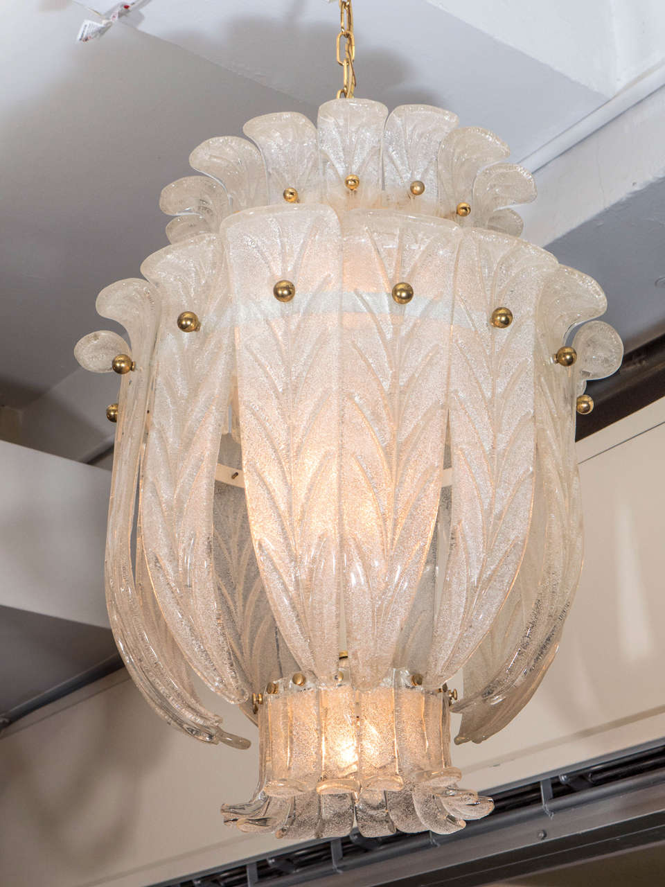 A vintage Italian chandelier by Barovier and Toso, with two-tiers of textured and stylistically curled glass leaves, detailed with veins, affixed to brass circular frames by round brass studs. Wiring and sockets to US standard, requires nine