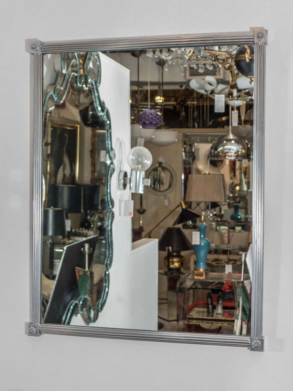 An Art Deco style Sherle Wagner mirror in a reeded brushed nickel frame, with square knuckle joints and rosettes. Good condition with age appropriate wear.