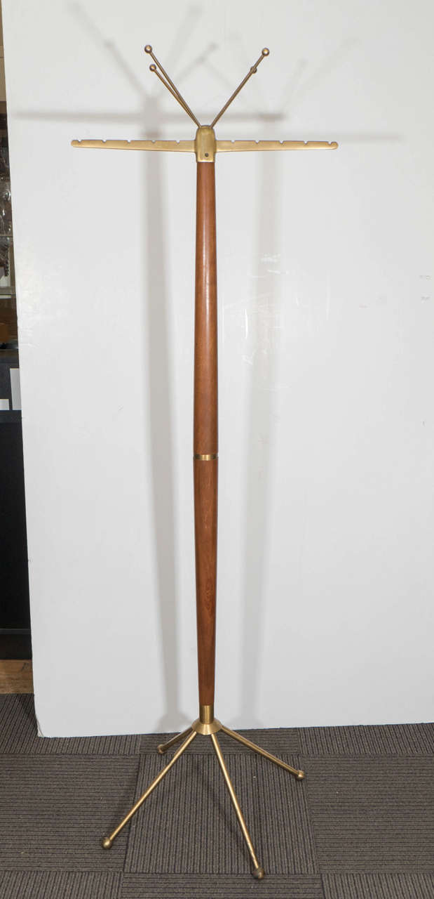 A vintage wooden tapered shape coat stand with brass band, in the style of Gio Ponti, with four legged solid brass base, hat tree and brass arms. Good vintage condition with age appropriate wear and patina. A few minor scratches and a small amount