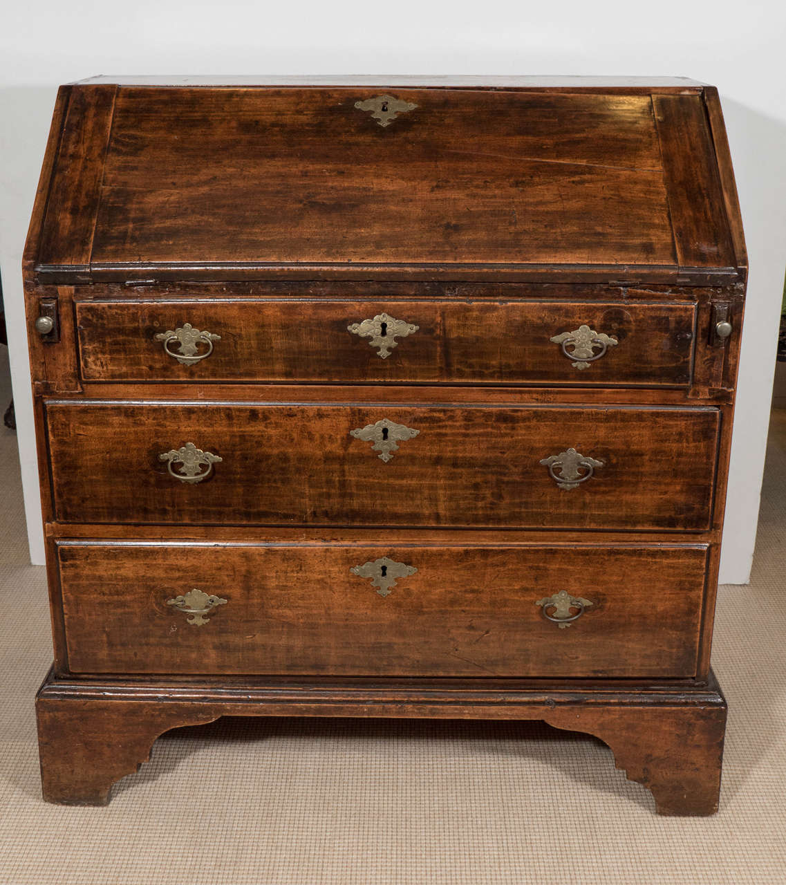 An 18th century English diminutive mahogany slant front desk or bureau with dove tail joints and original brass hardware. Good antique condition with age appropriate wear. The front top drawer needs to be repaired.