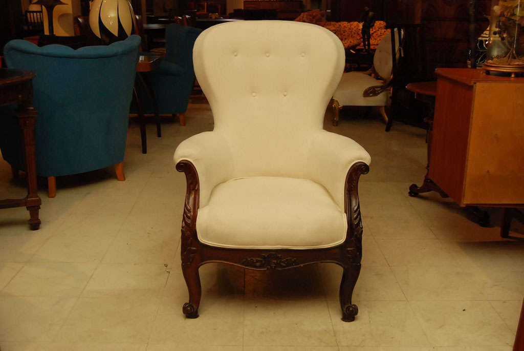 High backed Victorian armchair with mahogany framed, arms carved with flowers and leaves and scrolled feet.  Newly upholstered with white muslin