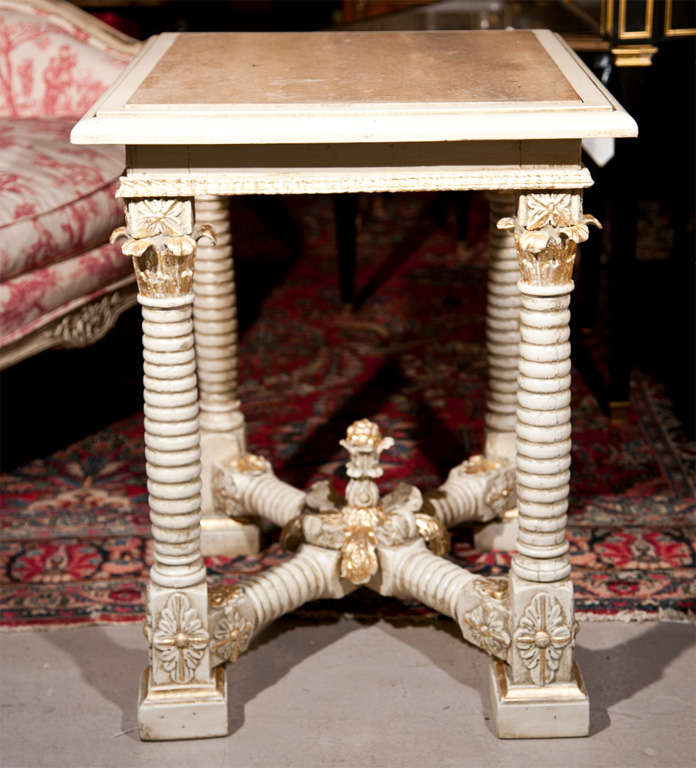 A Center Table by Maison Jansen having a framed marble top supported by four carved turned legs having bracket feet and a carved X base. Swedish white and gilt paint decorated.