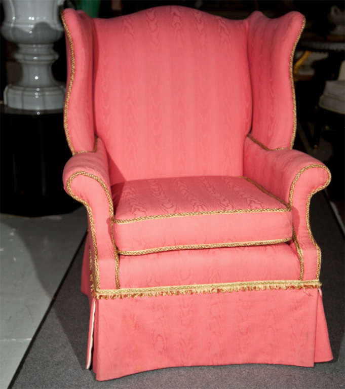 Pair of English Georgian style wing chairs, fully upholstered in pink fabric with beautiful traditional trimming. Loose cushioned seat.