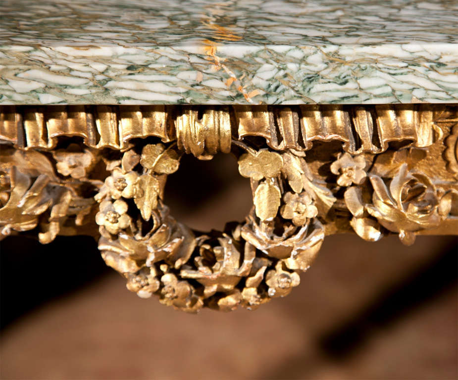 French Louis XVI style console table, beveled green and white marble atop an elegantly carved frieze, centered by a beautiful wreath crest, raised on four tapering fluted legs, joint by a stretcher decorated with beading and finial, raised on toupie