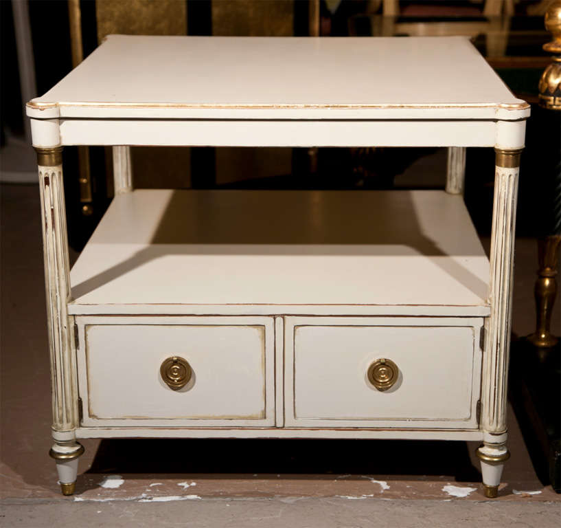 Pair of mid century white distress-painted end tables, the square top with gilded banding, raised on four fluted legs with a lower two-door cabinet.