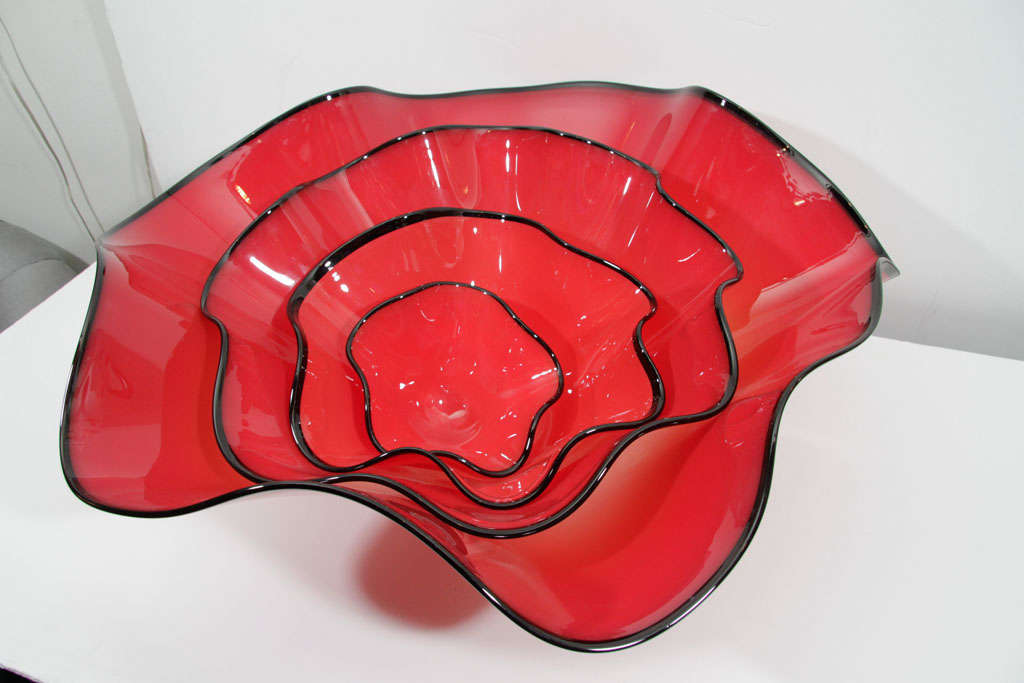 Stunning set of four red art glass nesting bowls. Each bowl features a fused black glass rim with a ruffled edge. Attributed to an artisan of the Chihuly Atelier.
