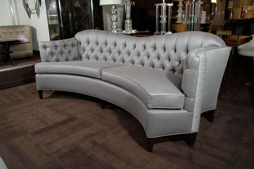 Glamorous 1940s Hollywood curved back sofa with tufted back, scrolled sides and rouched detailing. Newly upholstered in pewter silk/wool with ebonized Mahogany legs.