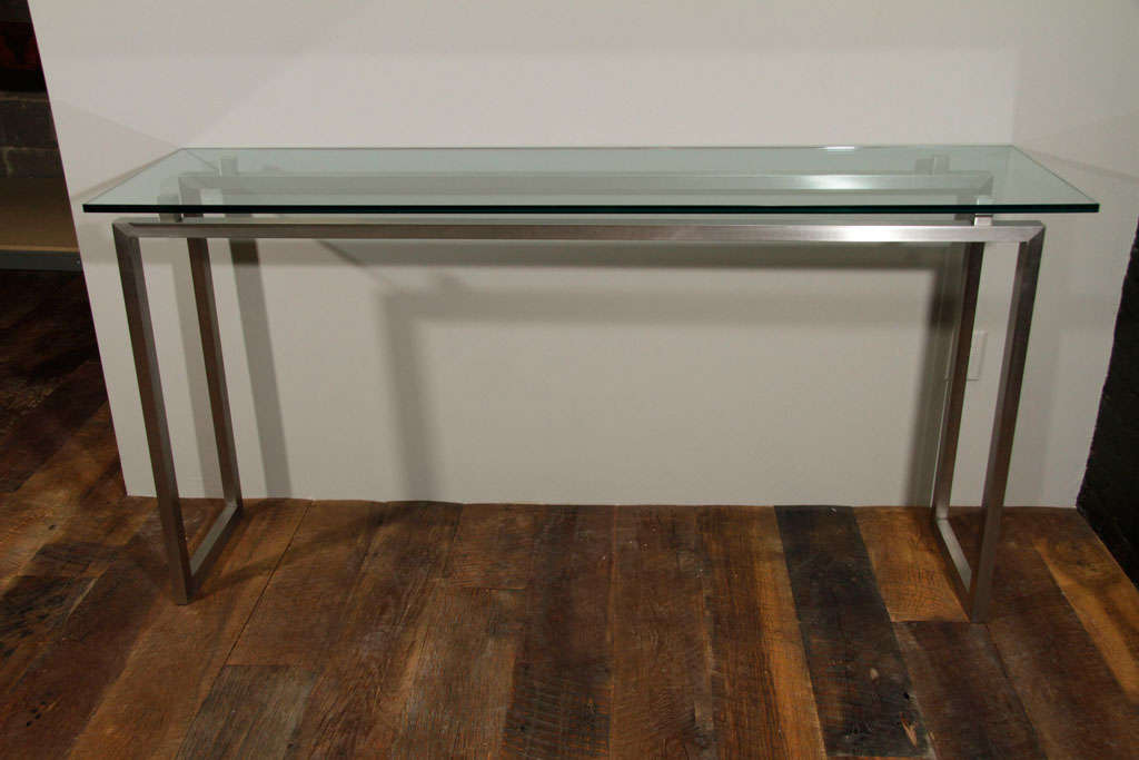 Brushed-metal console table with glass top.