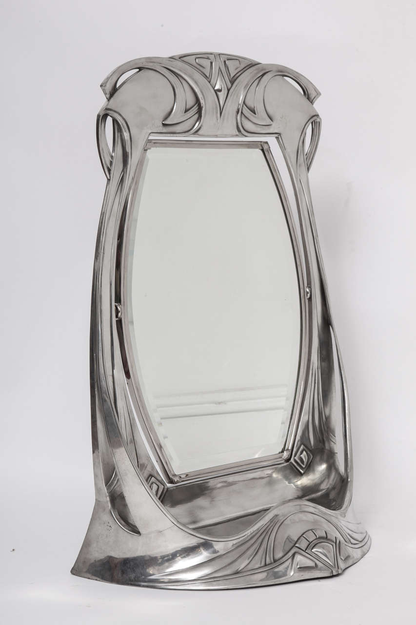 A WÜRTTEMBERGISCHE METALLWARENFABRIK Pewter and Wood Monumental Adjusting Vanity Mirror. Decorated with Highly Organic Jugendstil Designs, with a tray at the base of the mirror. It has the original hand beveled mirror and a hand carved wooden