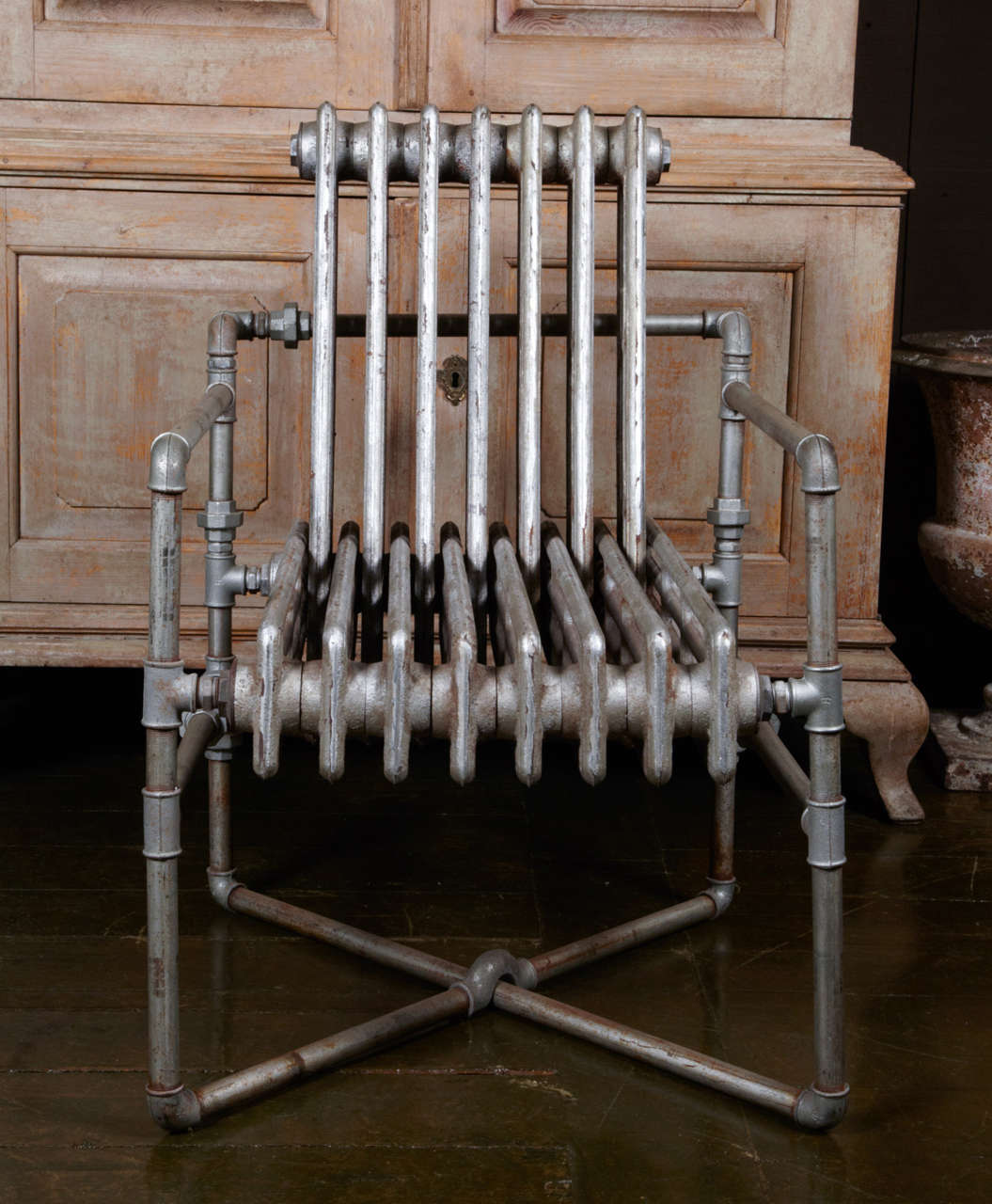 Incredibly clever industrial construction made with 2 cast iron heaters, and plumbery elements. Nice silvered patina on the parts. This piece is a chair but also a sculpture.