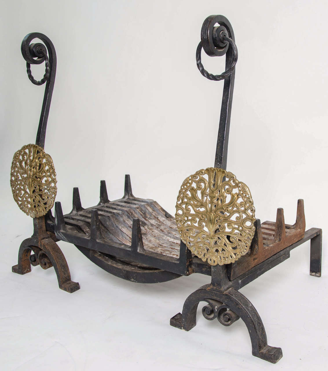 A large and refined pair of English Arts & Crafts andirons in wrought iron and bronze, supporting a matching grate.  
The wrought iron is beautifully decorated with geometrical patterns.