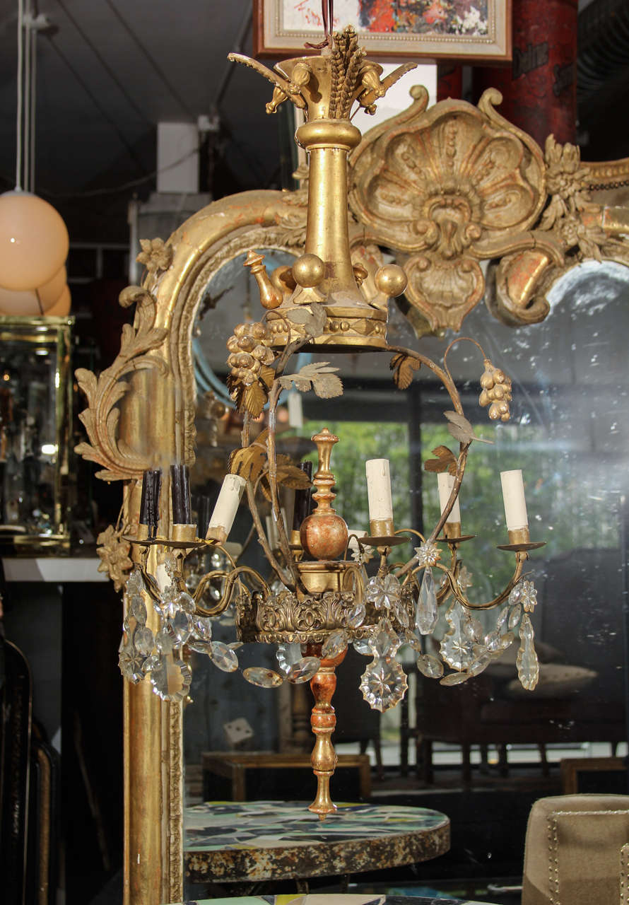 assembled in the 1930's of gilded wood, glass, crystal and metal this chandelier has its original wood candle stems, but we have taken a few out in photo to show how great it looks hung low over a table with candlelight.   as found- needs new wiring