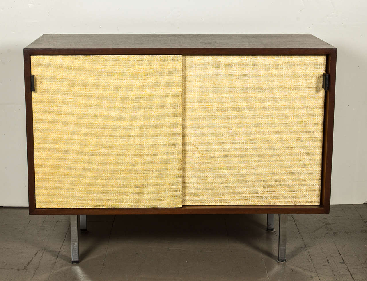 Florence Knoll walnut credenza with grass cloth doors and leather pulls.
Vintage item that has been refinished.