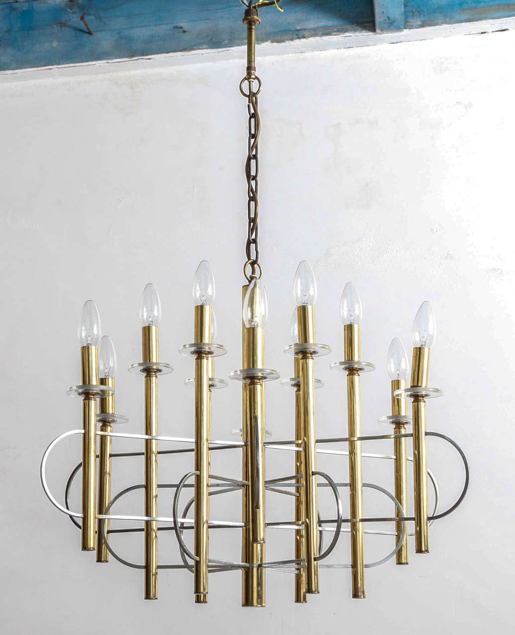 A stunning chandelier with twelve arms at alternating lengths, each holds a bulb, and elongated loop bands connecting them all finished in brass and brushed steel.By Sciolari. Italian, circa 1960.