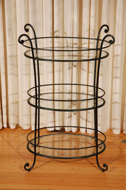 Beautifully crafted 1940's wrought iron table. Curved legs at top and bottom. Three oval shelves with gallery rails. Shelf surfaces measure 22