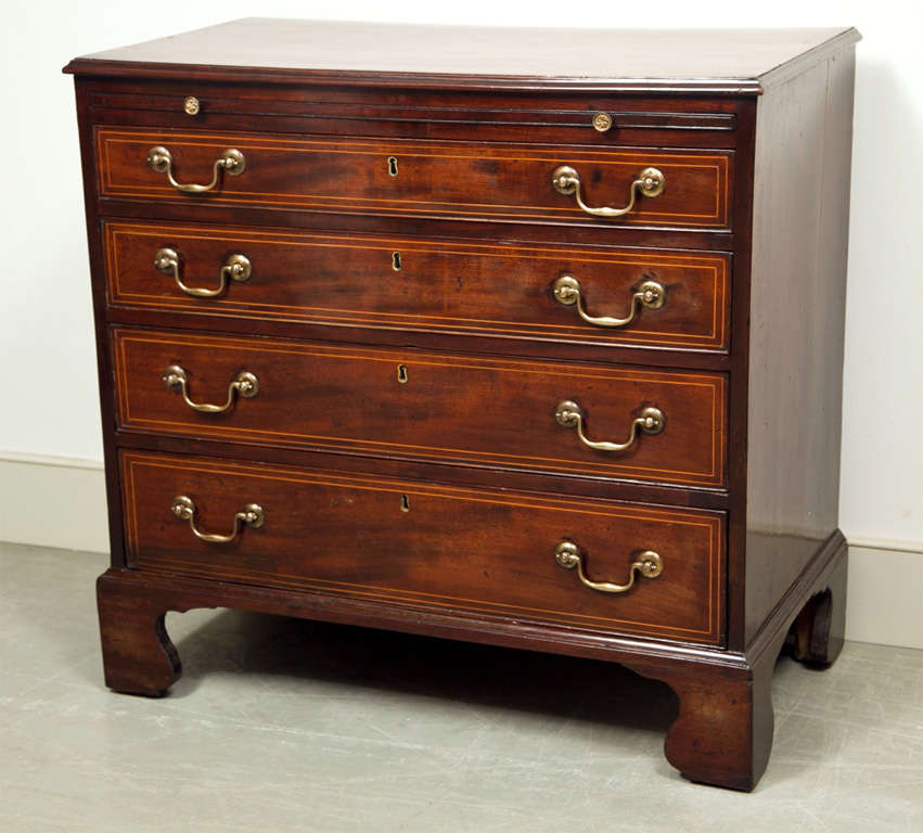 With its double string inlay of boxwood and handsome brasses, this antique bachelor's chest has just the right panache to look good in a bedroom or as an end table out in the public living room. Its depth of 18