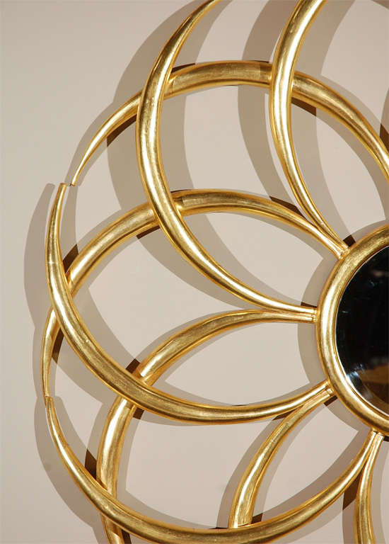 A graceful spiral sunburst mirror. Each of the ray is curved to form almost a floral pattern. Center convex mirror is 10 inches in diameter. Actual fixture is 41