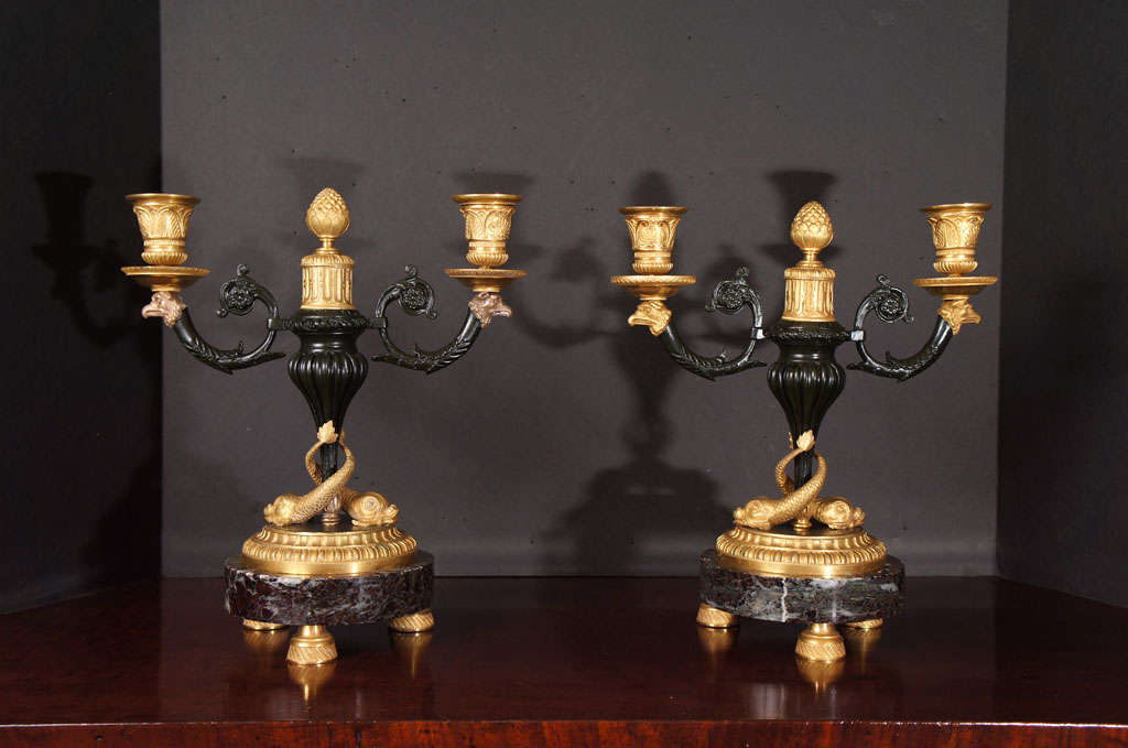 This pair of two-light candelabra are finely cast with great detail and fine hand chasing. The bronze work is in both matte and burnished gilding as well as patination making the work long and labor-intense creating a rich formal appearance. The