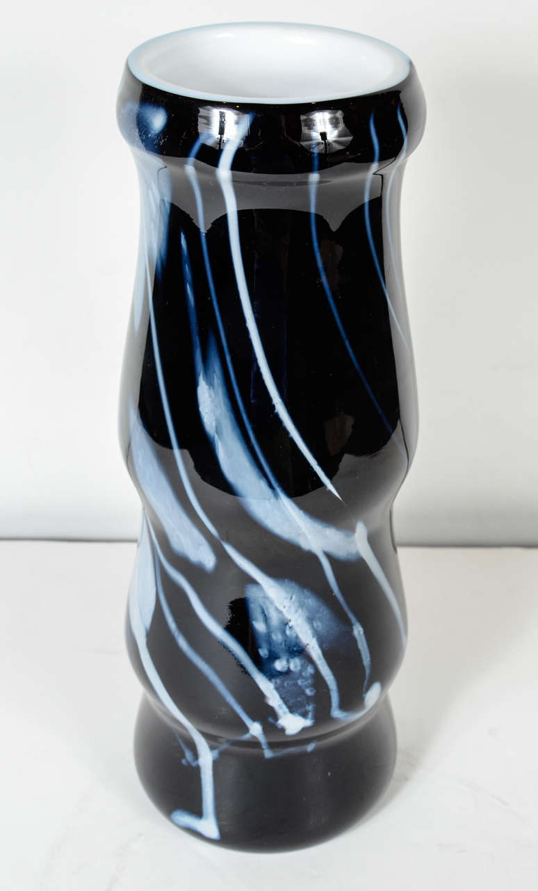 This modernist vase features a hand blown white feathered and linear glass design on a black glass background. It is signed Fostoria and dated 1978.