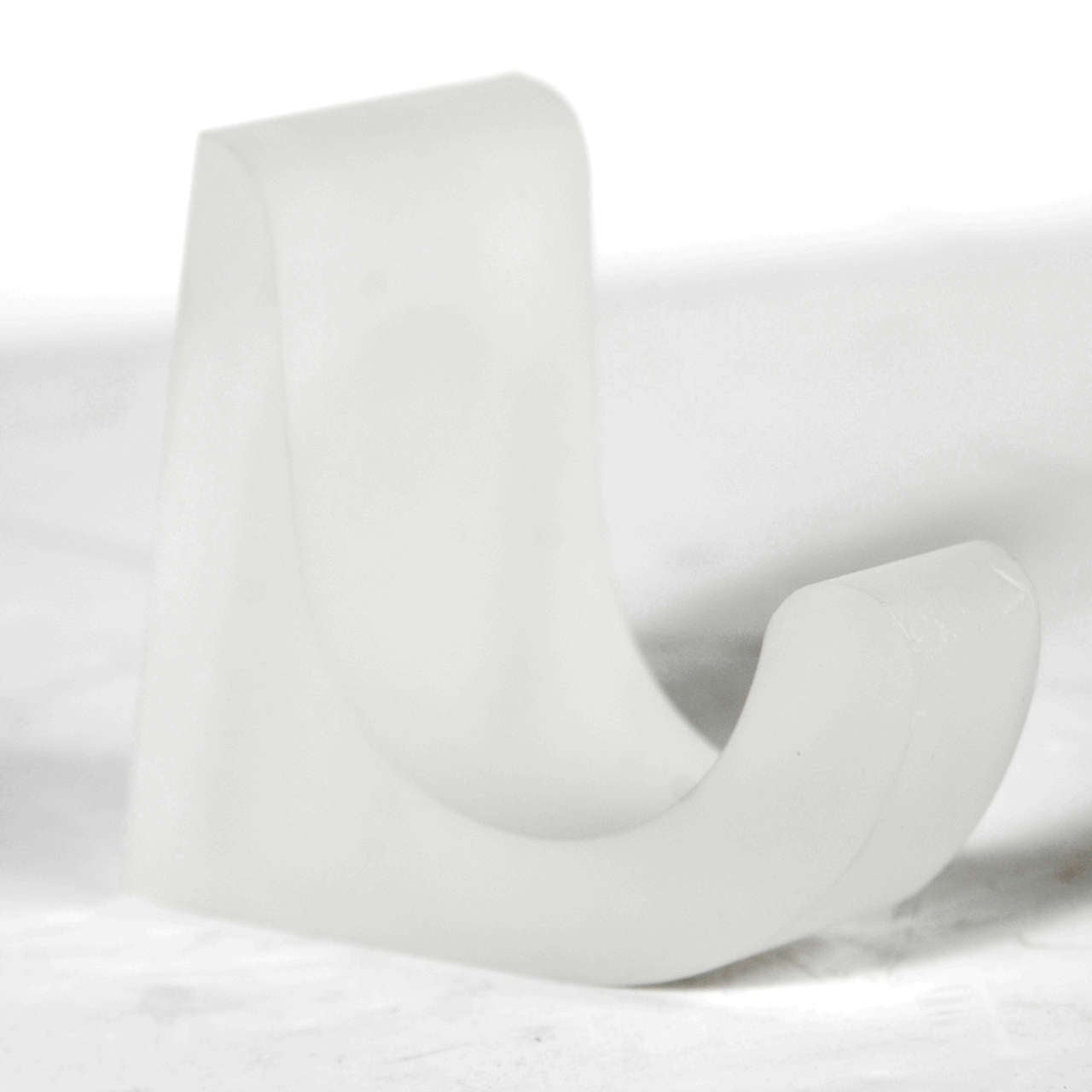 This vintage lucite robe hook features a semi-opaque finish resembling frosted glass and a simple muscular form is also incredibly dynamic with its wavelike undulating curve. This object eloquently showcases the aesthetic of 1970s modernist design,