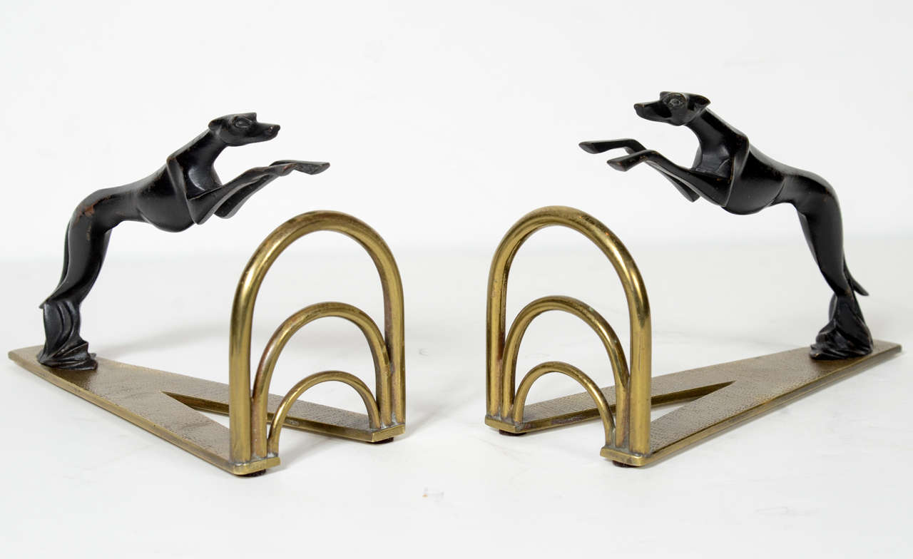 This Very sophisticated pair of  Art Deco book ends depicting leaping greyhouds over a stylized arched Art Deco rails.They are made of black enamel and brass in the manner of Hagenauer and they are signed Made in Vienna Austria.They are extremely
