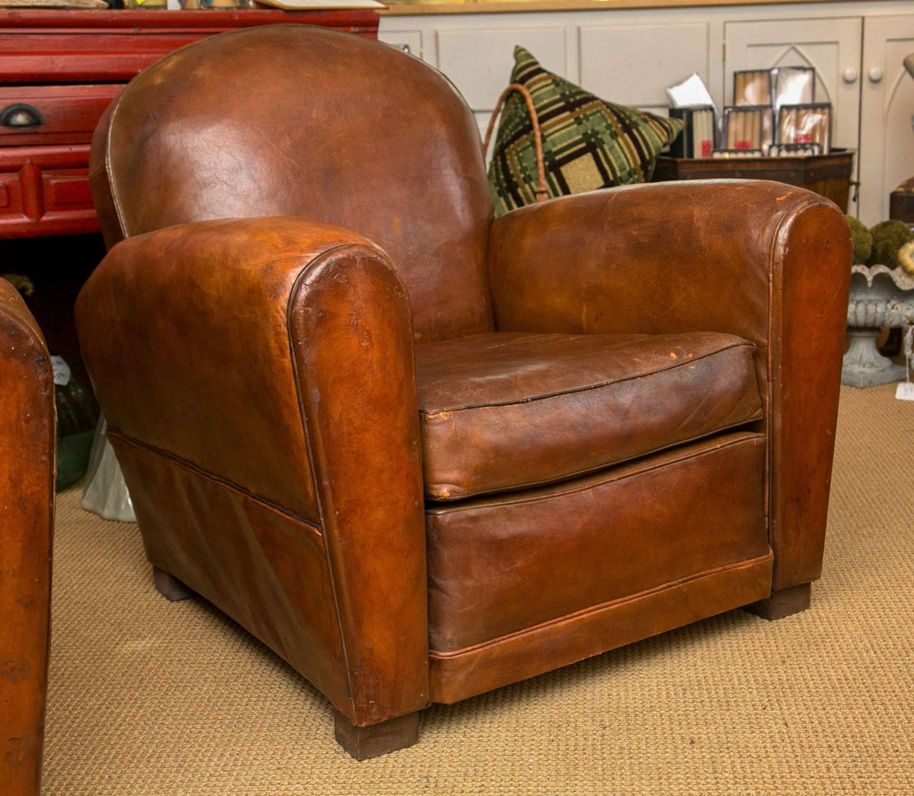 A rounded form cognac brown leather club chair on square wooden feet.