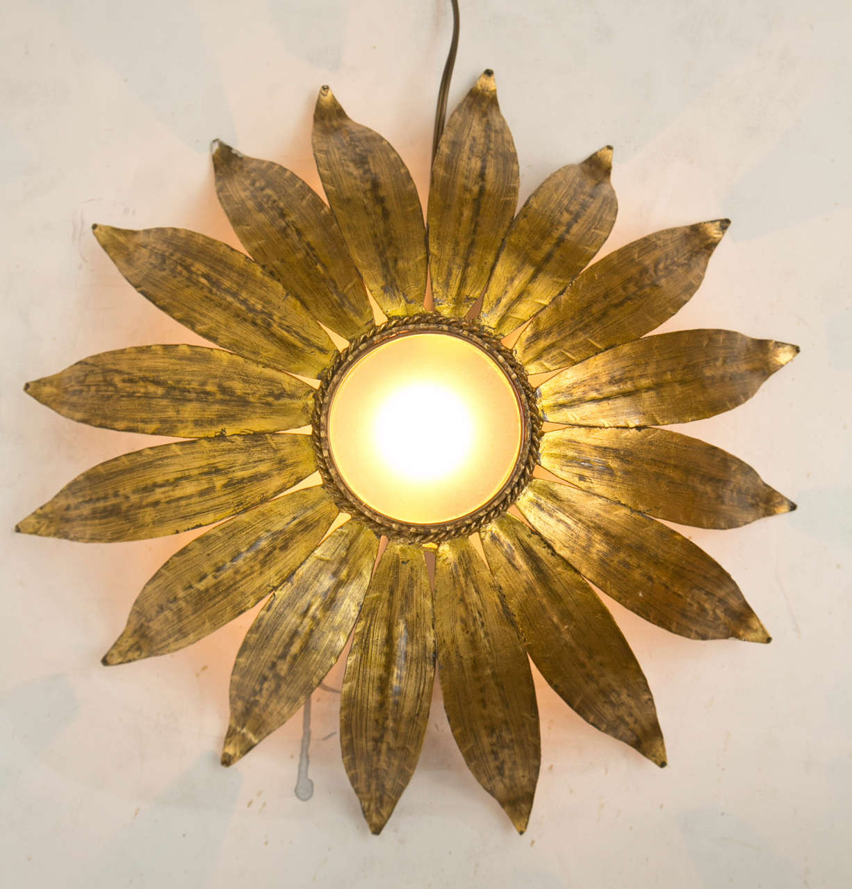 A lovely ceiling semi flush mount or wall light in the form of a sunburst. All hand-cut gilt metal with a frosted glass center shade. Please contact us for possible modifications that suit your needs.