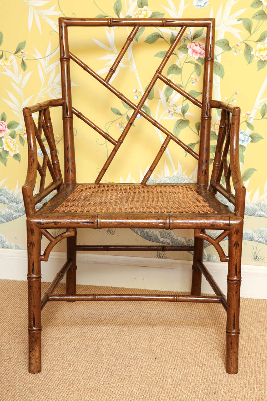 Antique pair of Chinese Chippendale period Cockpen open armchairs with carved and painted faux bamboo decoration, having loose cushions above a framed caned seat. English, circa 1765, now with cushions in ocelot red cafe by Cowtan and Tout.These