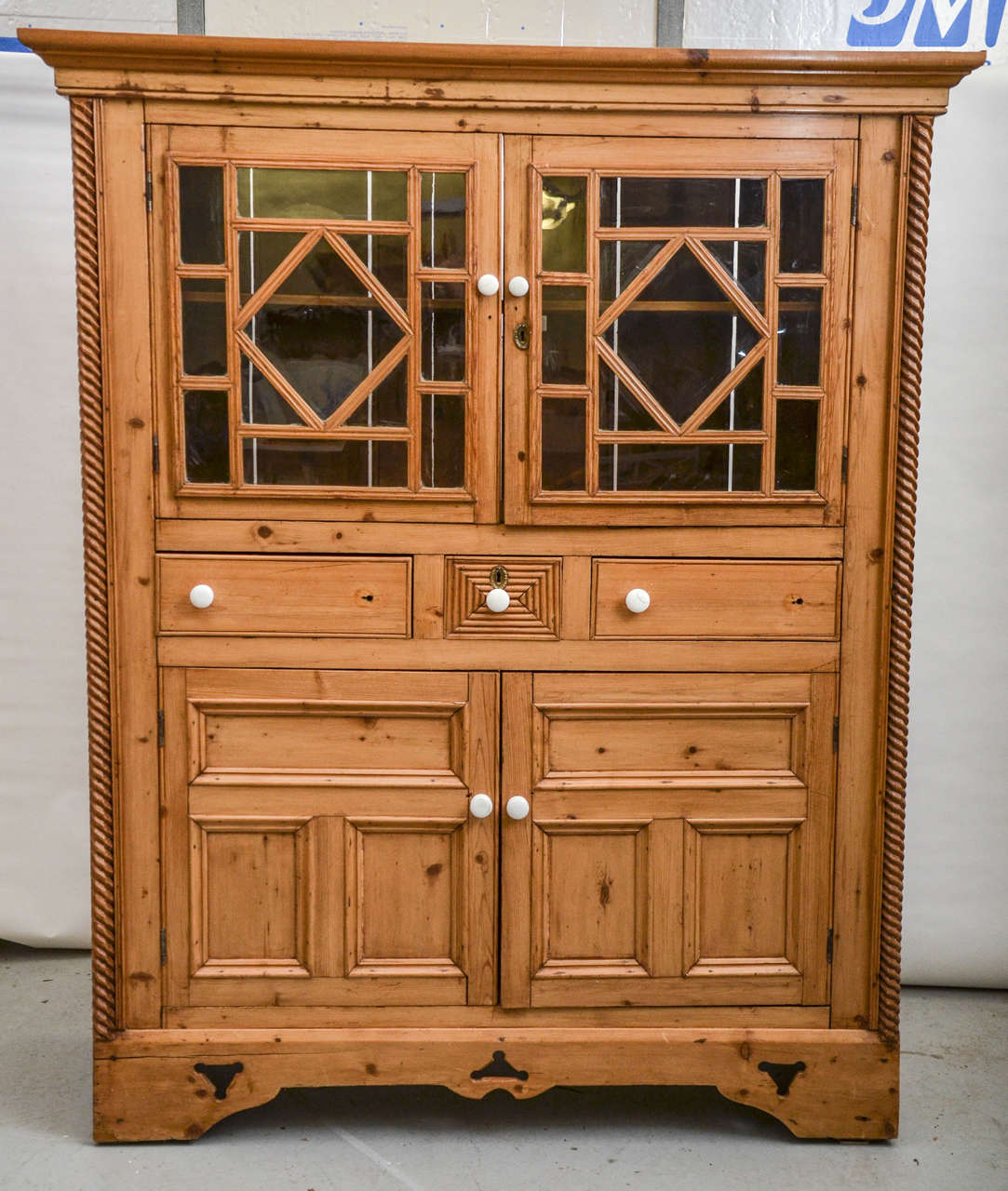 A fantastic and sturdy pine cabinet comprised of two windowed doors, three drawers and two lower doors, American, early 20th century. All drawers and cabinets in working order.