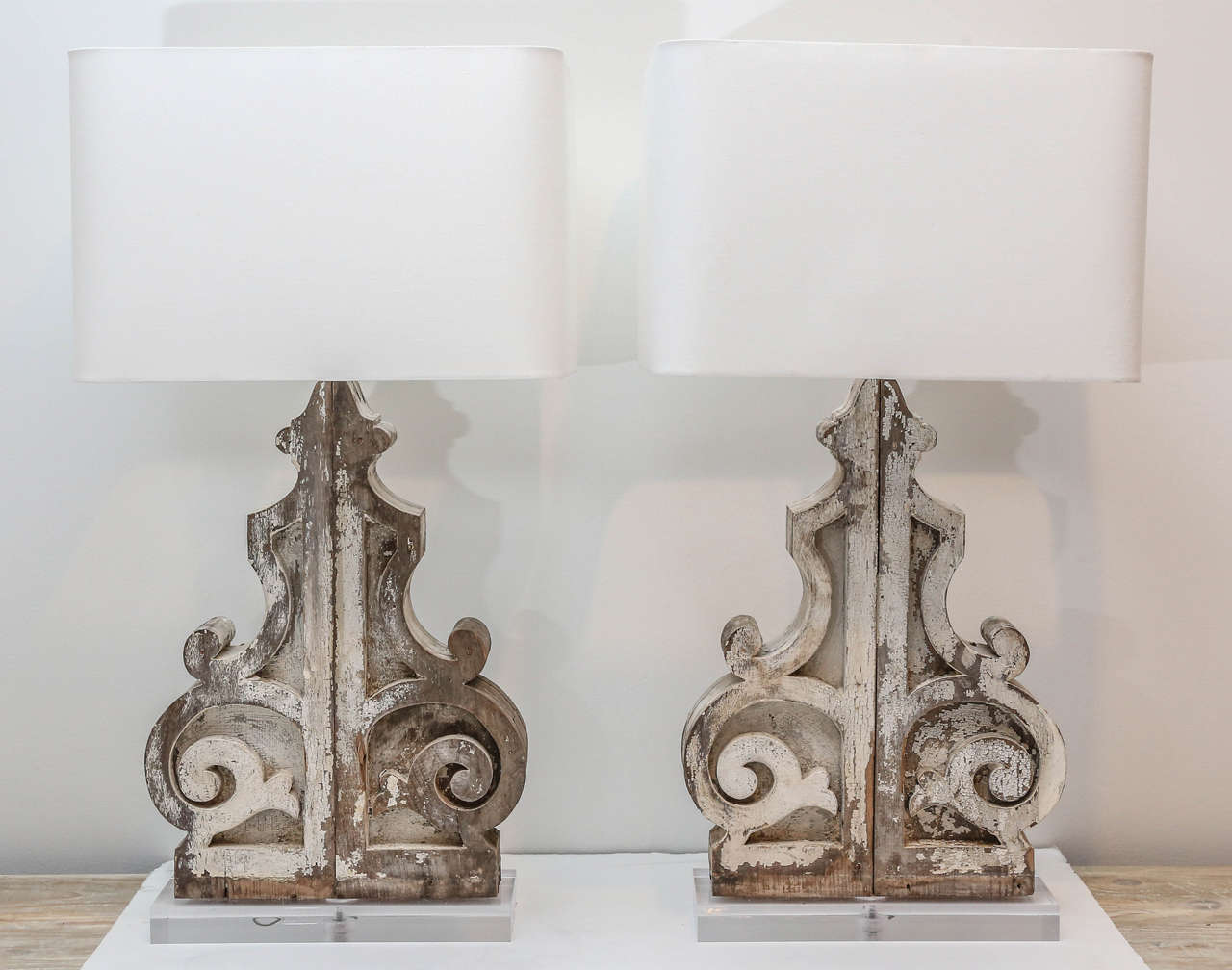 Four white painted 19th century corbels, mounted on Lucite bases, and newly wired as large pair of table lamps with rectangular rolled-edge linen shades.