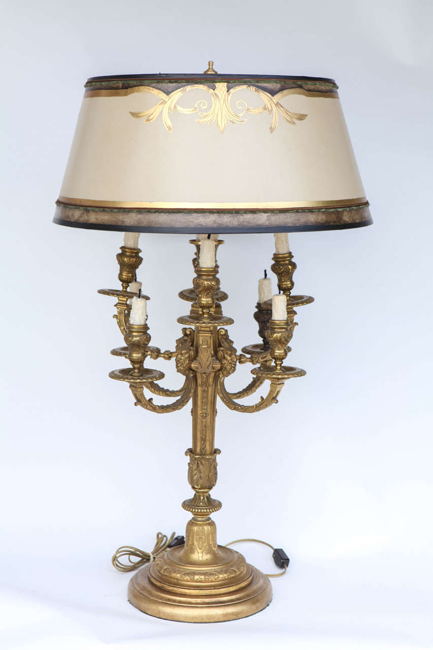 Pair of 19th century finely chased French doré bronze candelabras converted to lamps. The base diameter is 9 inches. The shades are included and are handmade of parchment paper. They are hand gilded and decorated. The lamps have been newly wired.
