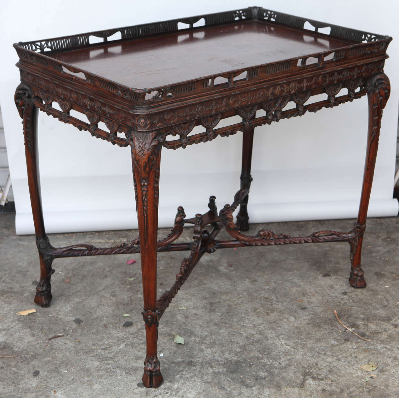 Late 19th century English finely carved mahogany tea table with stretcher. This table features ram's heads and a beautifully carved wood gallery.