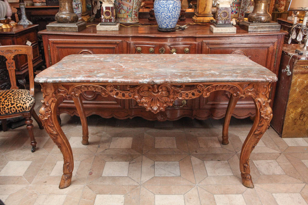 Late 18th century French carved walnut table with original marble top and hoof feet details.