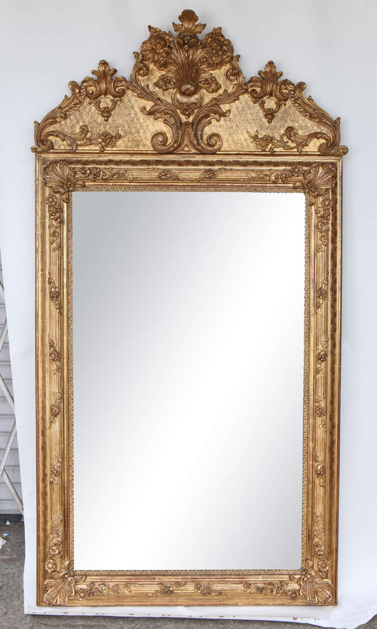 Early 19th century French carved and gilded mirror with crested top and an etched floral and leaf motif.