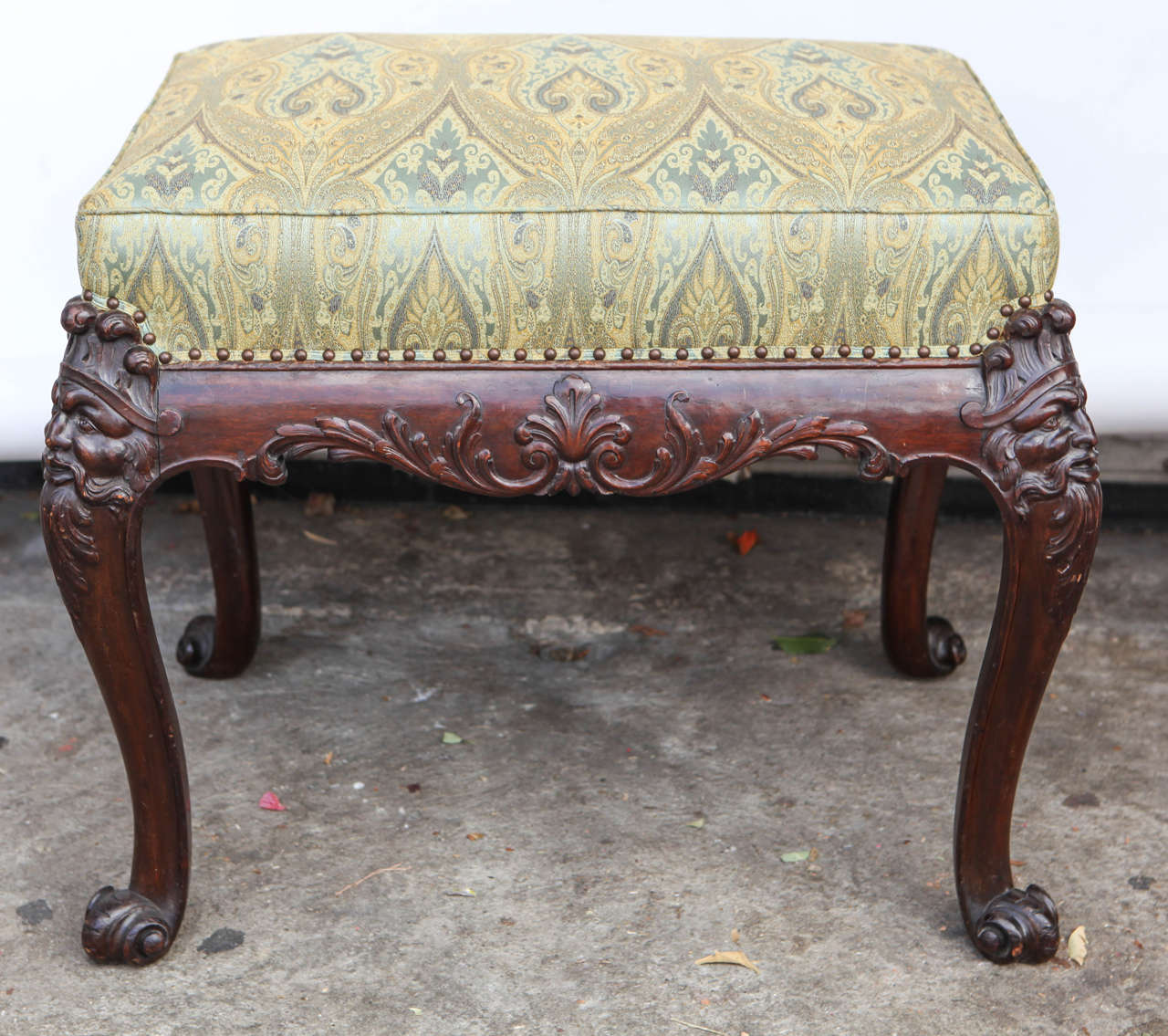 19th c. English carved Mahogany Bench or Stool with Green Silk Paisley Fabric.  The fine carving includes a face motif and scroll feet with nail head detail.