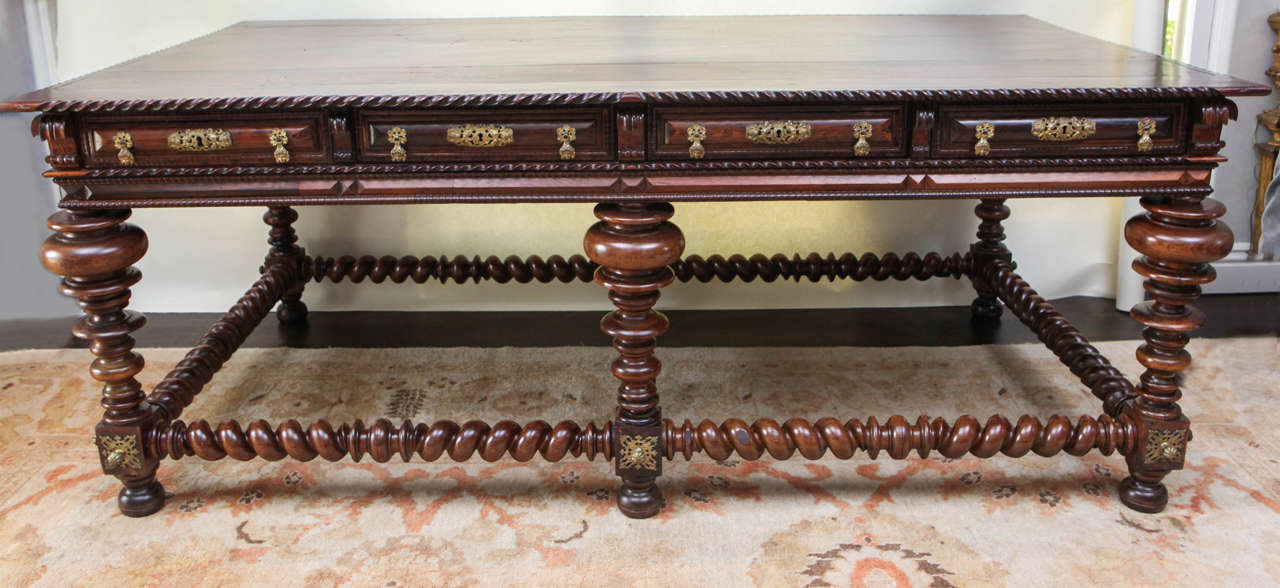 Early 19th century monumental Portuguese solid rosewood writing table or desk with four dovetail constructed working drawers. The finely carved writing table or desk has bun feet with twisted legs and stretcher. It can be floated in the middle of a