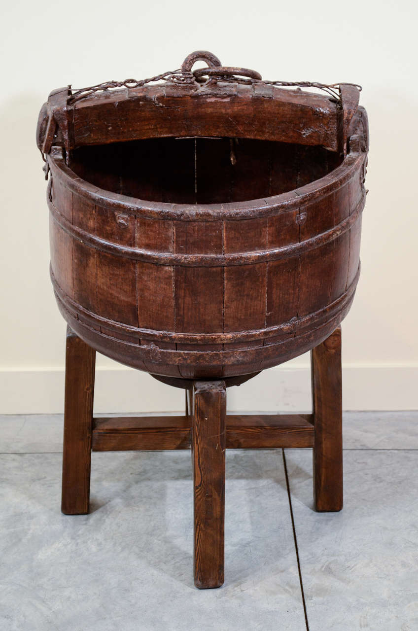 A large antique cypress water bucket with distinctive hand forged iron hardware. Includes stand.  From Shanxi Province, c.1880. 
BT346