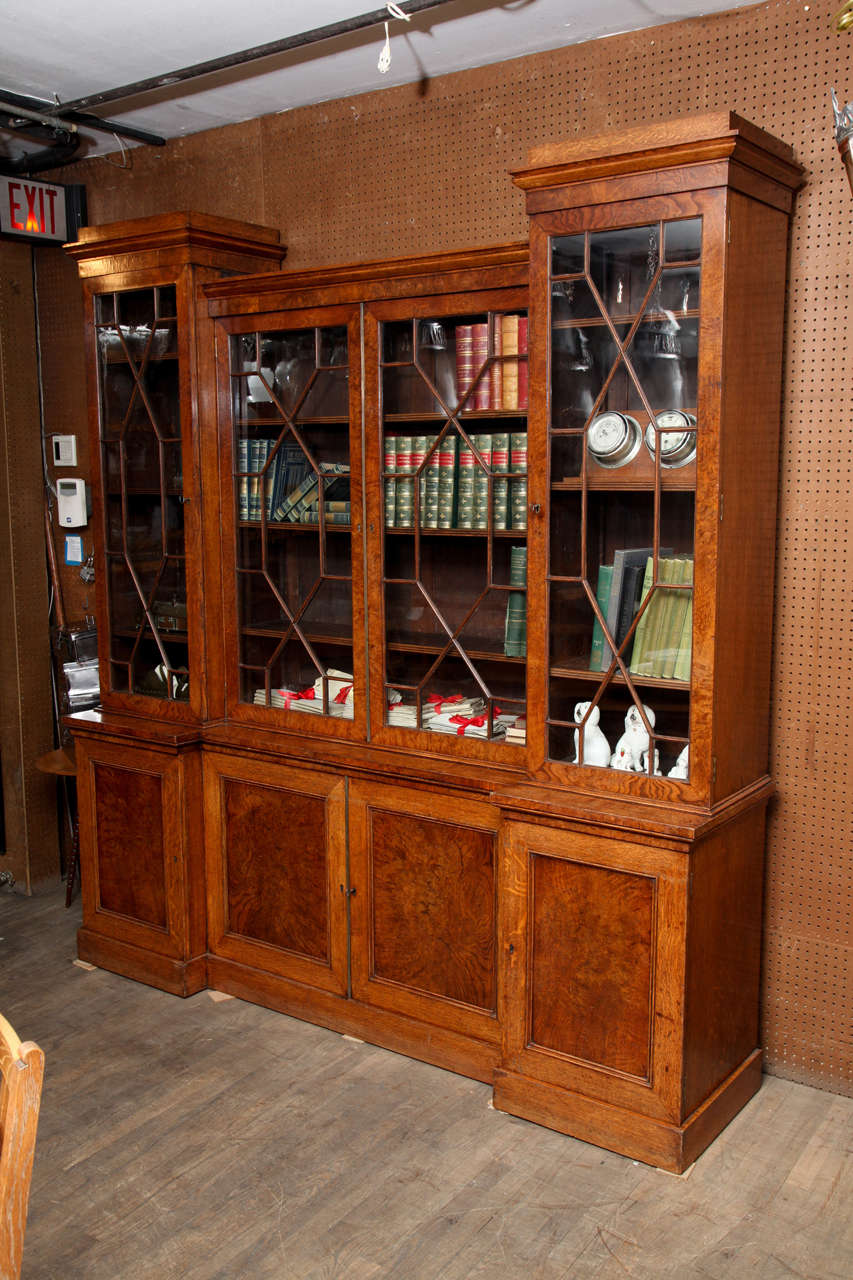 George IV Bookcase with glazed cabinet tops and doors. This bookcase was made with burled oak panels. This piece is rare because of it's size and shape. All doors and glass are original. All the shelves are adjustable.