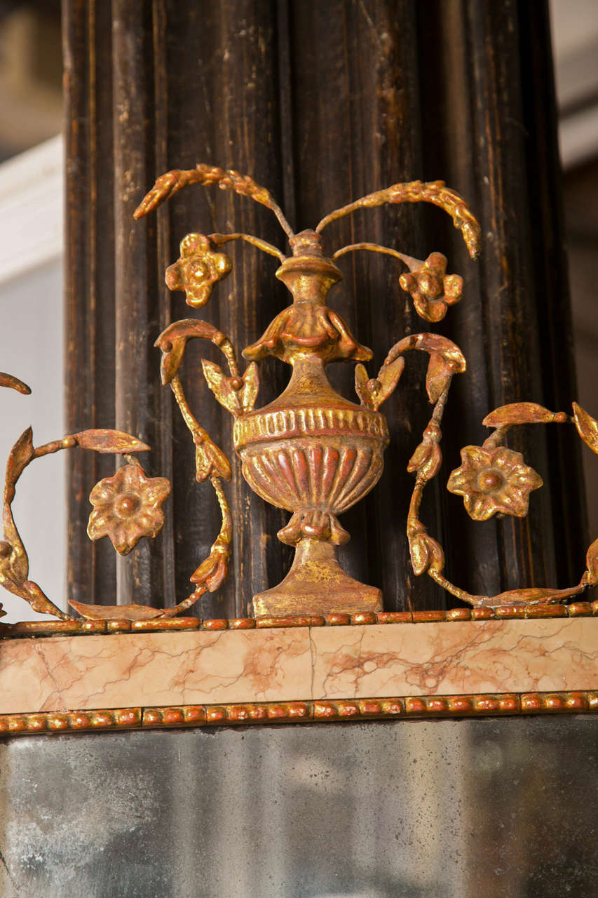 Miroir de style néoclassique datant de la fin du XVIIIe siècle, à glace rectangulaire surmontée d'un cadre en marbre et flanquée de montants en marbre, le plateau centré d'un décor d'urne en bois doré. Une pièce spectaculaire !