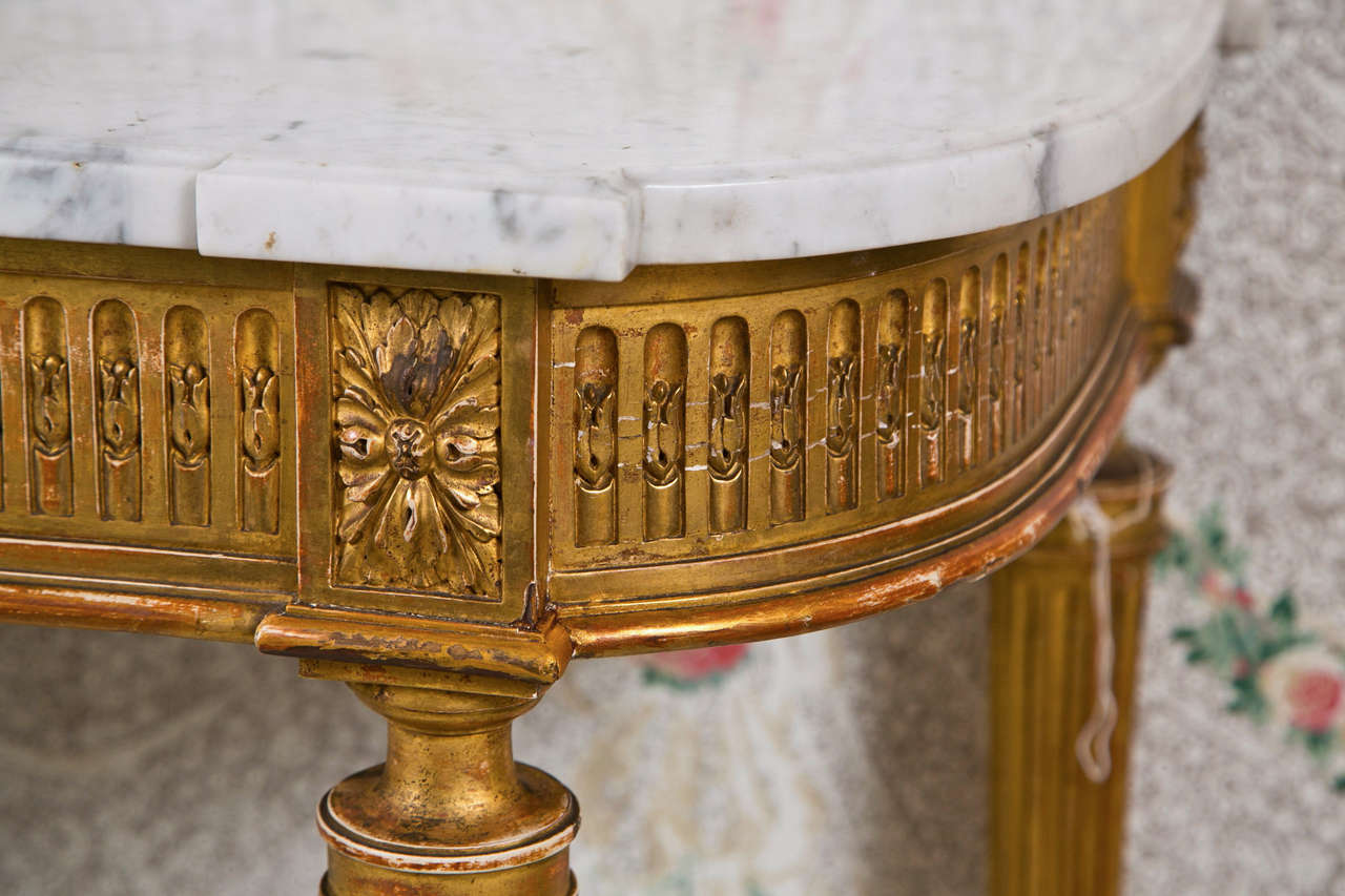A magnificent French bow-front console table in the style of Louis XVI, circa 1940s, the shaped white marble atop a cartouche frieze decorated with patera and rose carvings, supported on fluted tapering legs joined by an urn-form stretcher, raised
