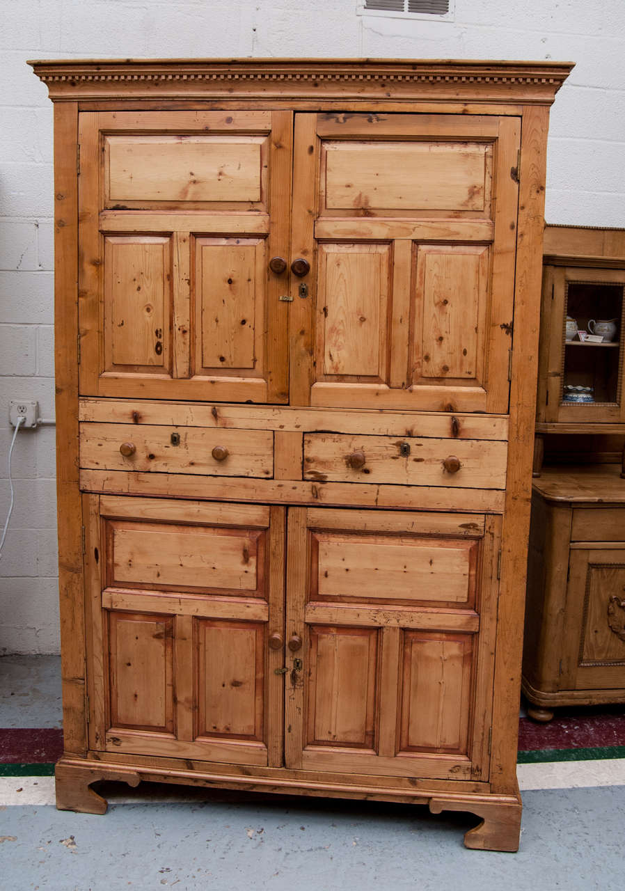 A fine example of an Irish Press cupboard featuring three panels to each side and three raised panels to each of four doors, separated by two lap-jointed drawers.  Typical Irish journeyman construction using available and found materials.