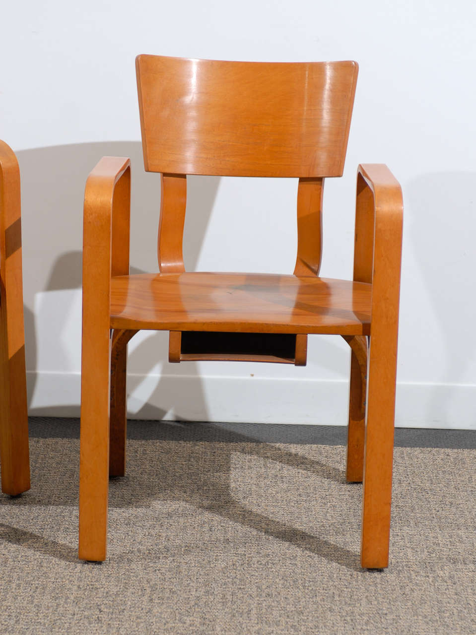 A handsome pair of bent plywood arm chairs by Thonet, Circa 1940's. A very rich and warm color, with great patina. Rescued from an abandoned church, they are complete with a hymnbook holder under the seat ! Very Good Vintage Condition. The chairs