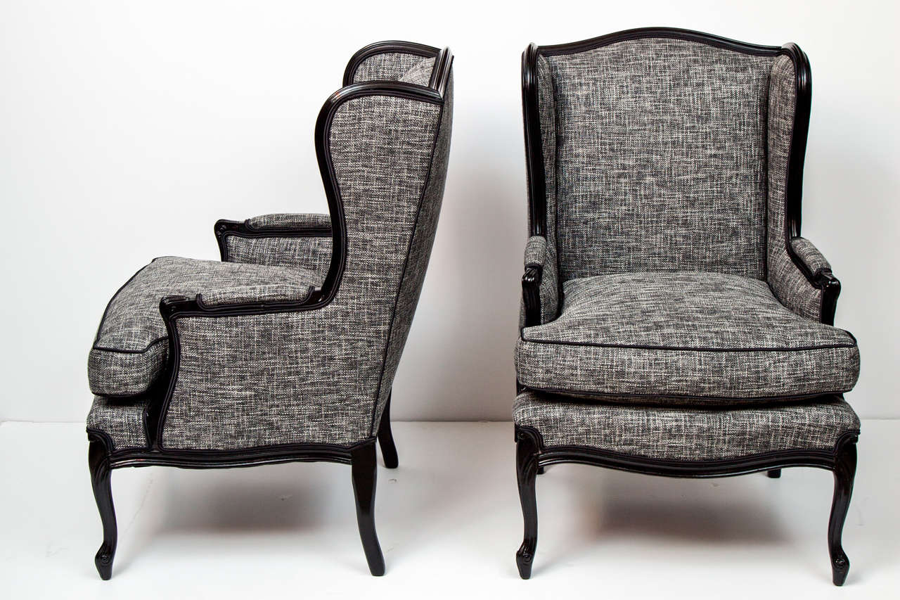 Very comfortable pair of tall wingback chairs, c 1950. Wood frame is lacquered black with a tweedy cotton/linen fabric. A very comfortable chair.